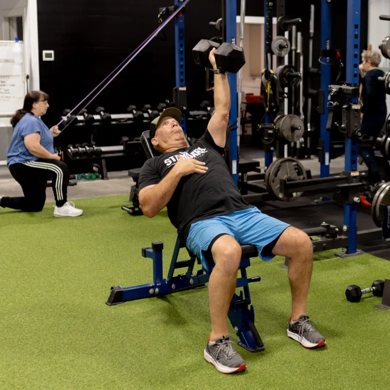 Member performing single arm incline bench press